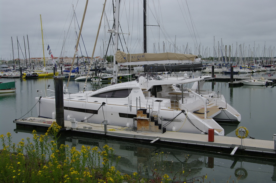A modern catamaran from the Privilege series in Le Sables d'Olonne harbour. On the left in the background is one of the famous Open 60.