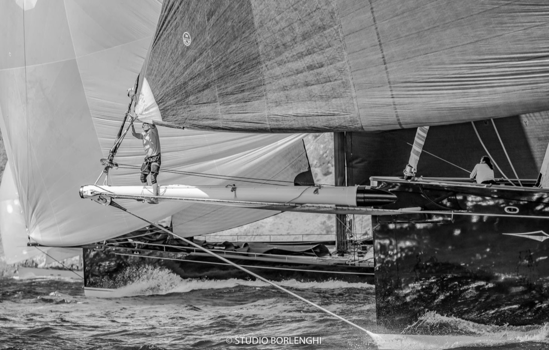 Bowman works on the bow of Hetairos, the largest boat in the fleet and winner of the St. Barth Bucket 2019 regatta. It is a pity that the black and white image does not convey the amazing dark green hull color of this yacht. In this shot, Hetairos competes with MySong.