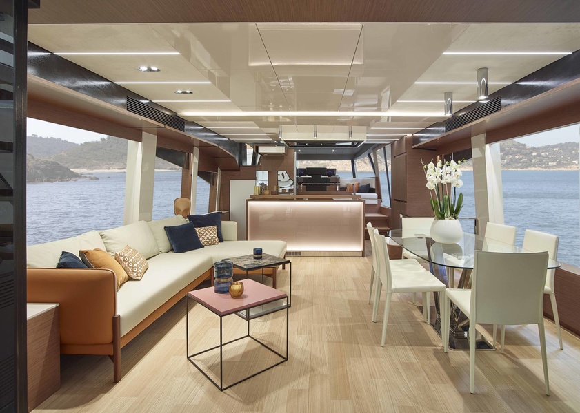 Main deck salon. Thanks to the wide door and glazing, the cockpit seems to flow smoothly into the interior of the yacht. The absence of external side aisles made the saloon as wide as possible. The TV is lowered from the ceiling. 